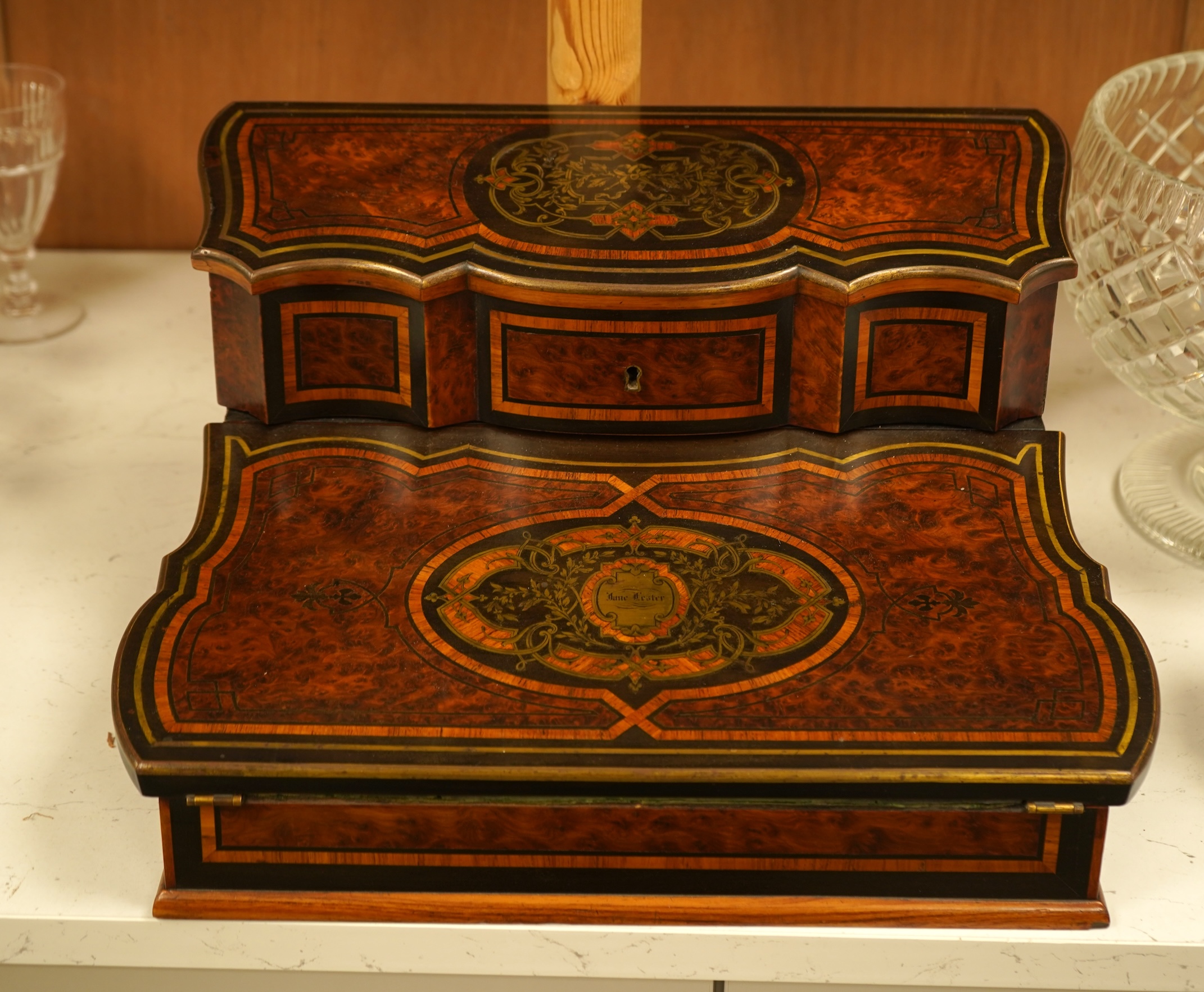 A 19th century French brass inlaid, tulip banded amboyna writing casket, the brass panel inscribed ‘Jane Lester’, 40cm wide
